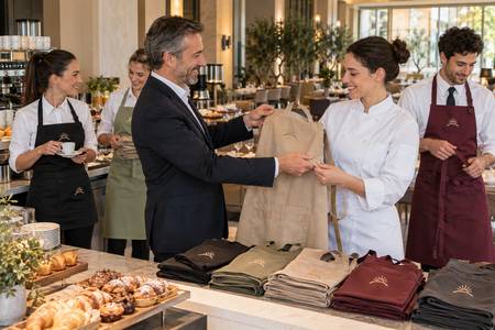 Entrega de delantales personalizados al personal de un hotel con un símbolo común.